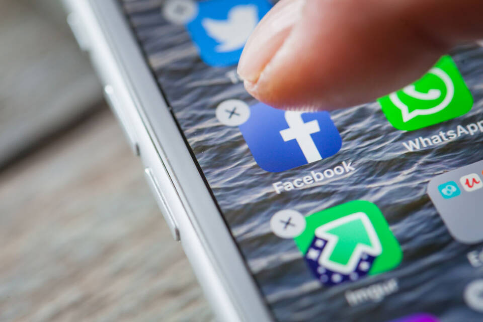 Finger deletes Facebook app on iPhone screen, shot in BERLIN, GERMANY - JUNE 6, 2018