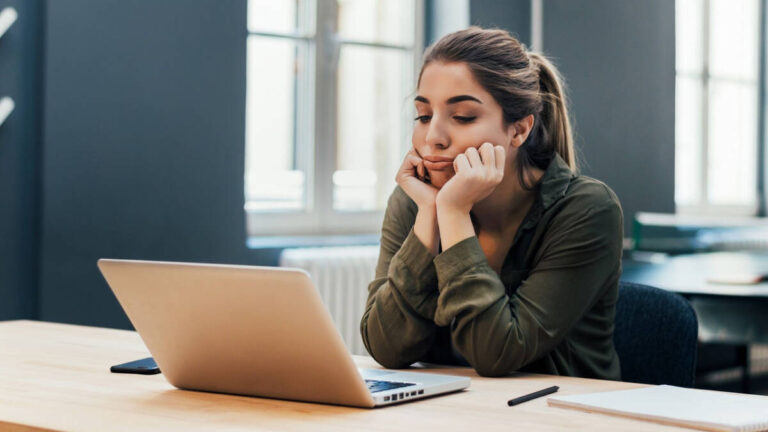 Portrait of young bored attractive female student looking at laptop